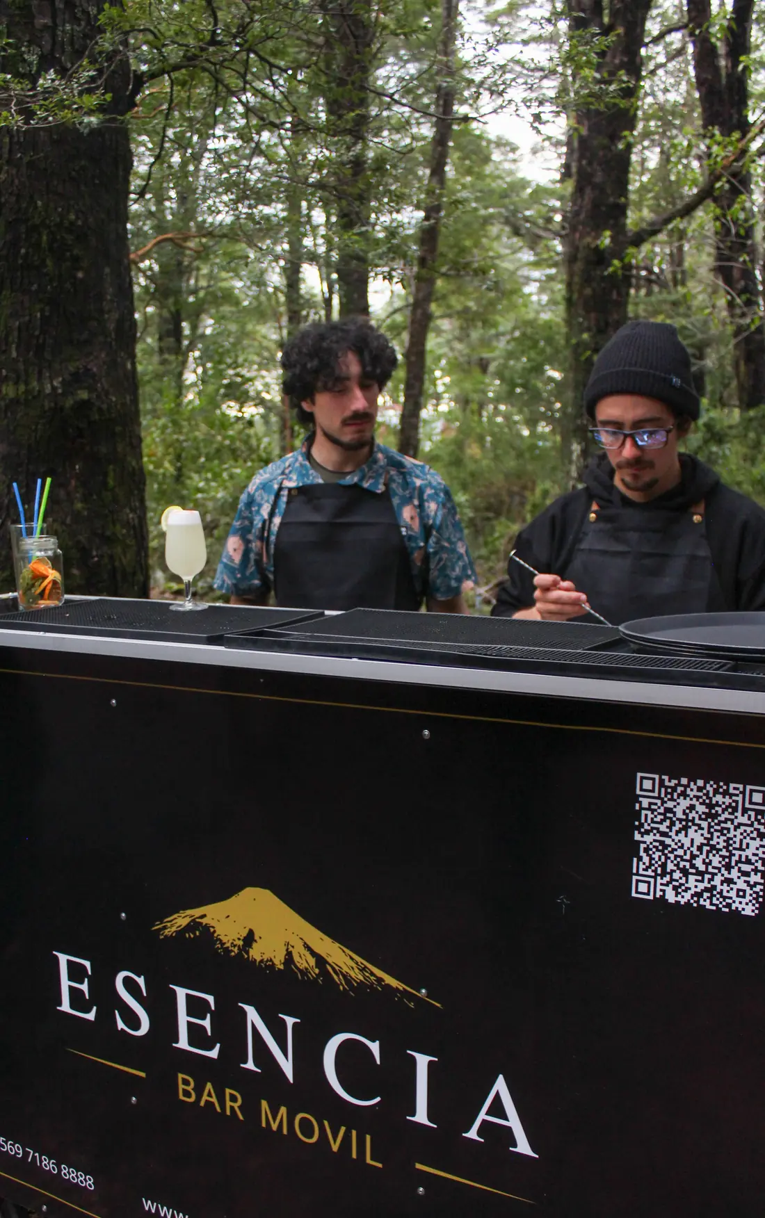 Dos bartenders de Esencia preparan cócteles en su barra negra en medio del bosque