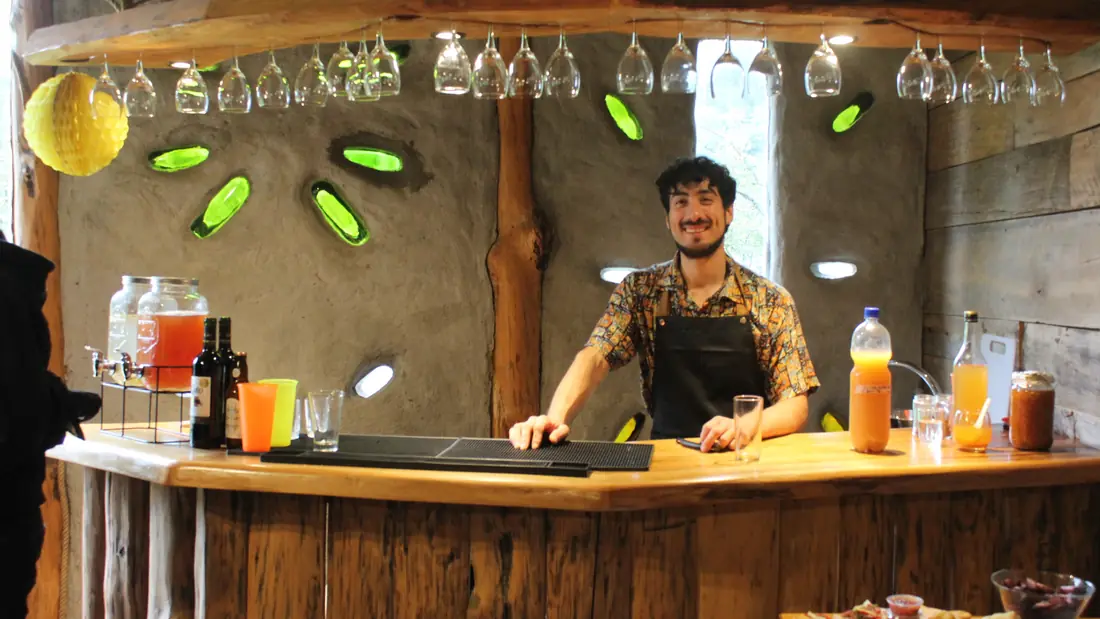 Bartender de Esencia atiende una barra de madera con jugos y destilados